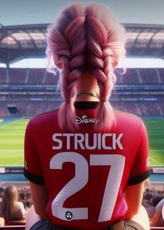 a woman with pink hair wearing a red shirt in front of a soccer stadium and looking at the camera