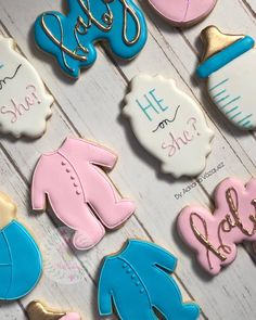 baby shower cookies with blue and pink icing on a white wooden table next to other decorated cookies