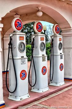 three old gas pumps with the numbers seventy on them are lined up in a row