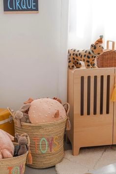 two baskets filled with stuffed animals next to a crib