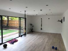 an empty gym room with hard wood floors and sliding glass doors leading to the back yard