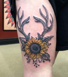 a sunflower and antlers tattoo on the leg