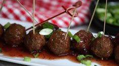 meatballs with sauce and green onions on a white plate, ready to be eaten