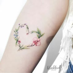 a woman's arm with a flower heart tattoo on the left side of her arm