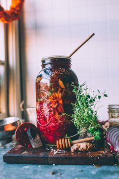 a jar filled with lots of food sitting on top of a wooden table next to other items