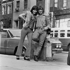 two women standing next to each other near a pole