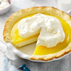 there is a pie with whipped cream on top in the bowl next to a knife and fork