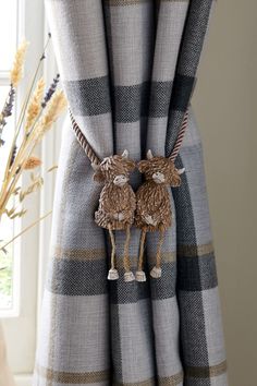 the curtains are decorated with two poodles hanging from it's rod ends