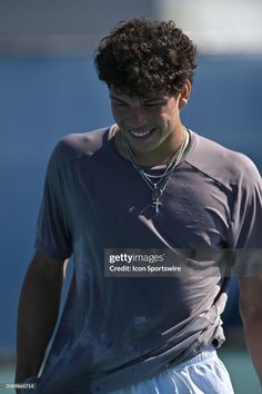 a young man smiling while holding a tennis racquet in his hand stock photo