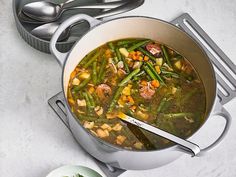 a pot filled with soup next to some spoons and a plate on the table