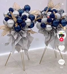 two silver and blue balloons are on top of metal stands with gold leaves in the middle