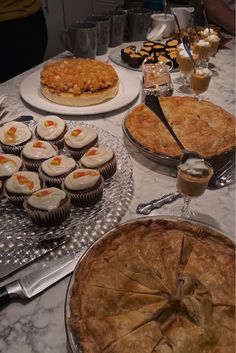 a table topped with lots of pies and cupcakes