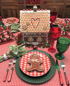 a table set for christmas with gingerbread cookies on the plate and place settings in front of it