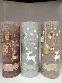 three christmas candles are decorated with gold, silver and green decorations on them as if they were made out of toilet paper