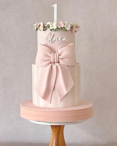 a pink and white cake with a bow on top