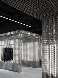 an empty room with clothes hanging from the ceiling and metal grids on the walls