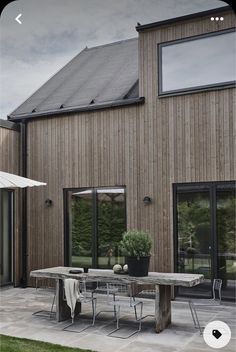 an outdoor table and chairs in front of a wooden building with glass doors on the outside