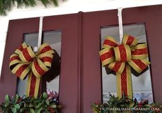 two christmas wreaths with bows hanging on the front of a door, decorated for holiday