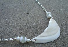 a white shell is attached to a silver chain