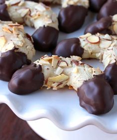 chocolate covered cookies on a white plate with almonds in the middle and coconut flakes