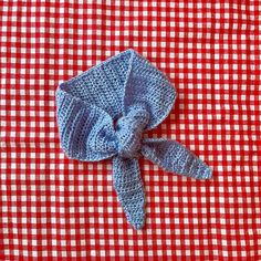 a red and white checkered table cloth with a blue crochet bow on it