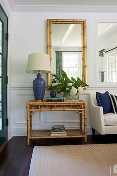 a living room with a couch, mirror and lamp on the side table in front of it