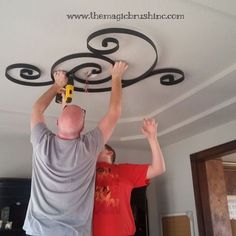 two men are working on a ceiling fixture