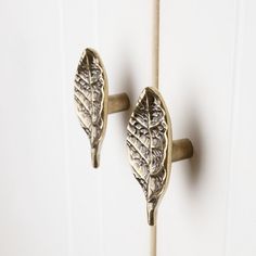 two metal leaves are on the handle of a white door with wood trimmings