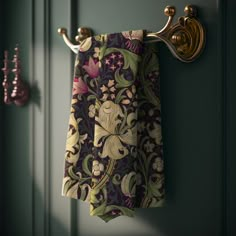 a pair of towels hanging on a towel rack next to a green door with gold handles