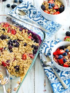 two bowls of fruit and oatmeal are on the table with spoons