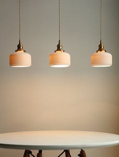 three lamps are hanging over a white table