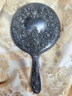 an ornate spoon is sitting on a gold and white fabric