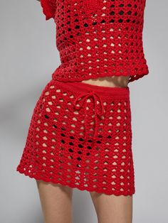 a woman wearing a red crochet top and shorts