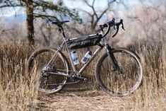 a bike parked on the side of a dirt road in a field with tall grass