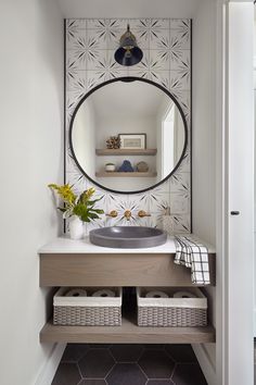 a bathroom with a round mirror above the sink and baskets under the counter below it