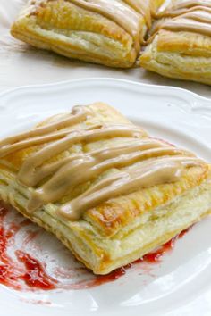 two pastries sitting on top of a white plate covered in sauce and drizzled with icing