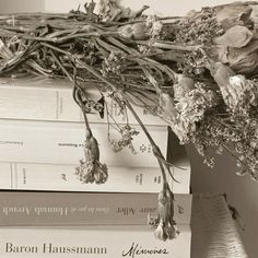 a stack of books sitting on top of each other with dried flowers hanging from them