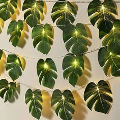 some green leaves are hanging from a string with lights in the shape of heart shaped leaves