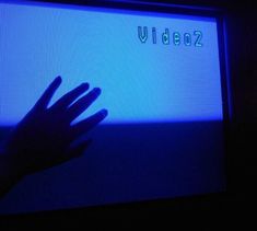 a person's hand on the screen of a television with video2 written on it