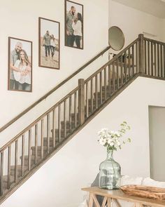 there is a vase with flowers on the table in front of some pictures and stairs