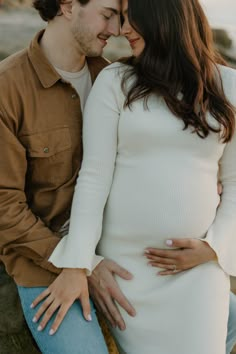 a pregnant couple cuddles and smiles at each other