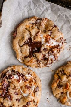 three chocolate chip cookies sitting on top of parchment paper