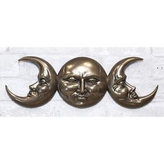 three bronze moon and man's face on a white brick wall