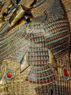 an ancient egyptian mask is shown in gold and blue colors, with red stones on the face