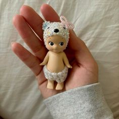 a hand holding a tiny doll wearing a diaper