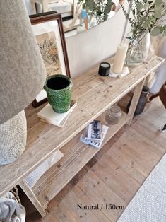 a wooden table topped with a vase filled with flowers next to a mirror and lamp