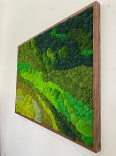 a green wall hanging on the side of a white wall next to a wooden frame