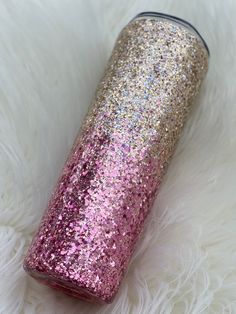 a pink and gold glitter tumbler sitting on white fur