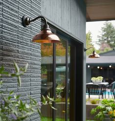 an outdoor light is hanging on the side of a building next to a patio with chairs and tables