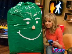 a woman sitting next to a giant green bag